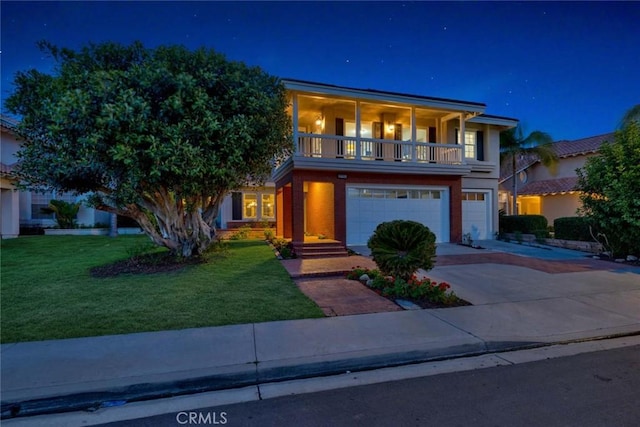 view of front of house featuring a garage, a lawn, driveway, and a balcony