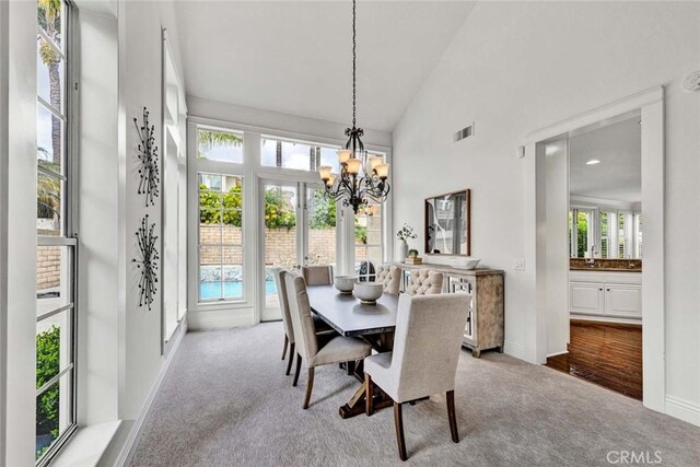 carpeted dining room featuring an inviting chandelier, baseboards, visible vents, and high vaulted ceiling