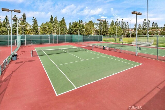 view of tennis court with community basketball court and fence