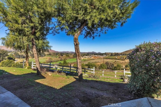 view of yard with a rural view, a mountain view, and fence