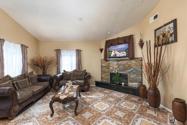 living area with visible vents, a fireplace, baseboards, and lofted ceiling