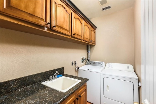 clothes washing area featuring a sink, visible vents, cabinet space, and independent washer and dryer