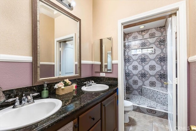 bathroom with a shower stall, toilet, double vanity, and a sink