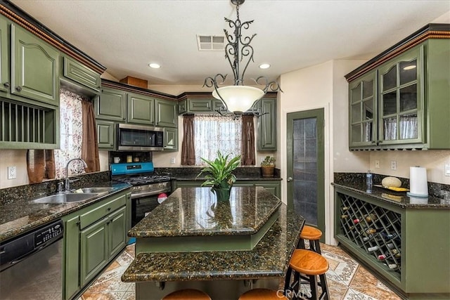 kitchen featuring appliances with stainless steel finishes, a breakfast bar, green cabinets, and a sink