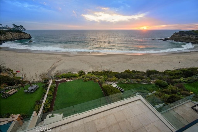 aerial view at dusk with a beach view and a water view