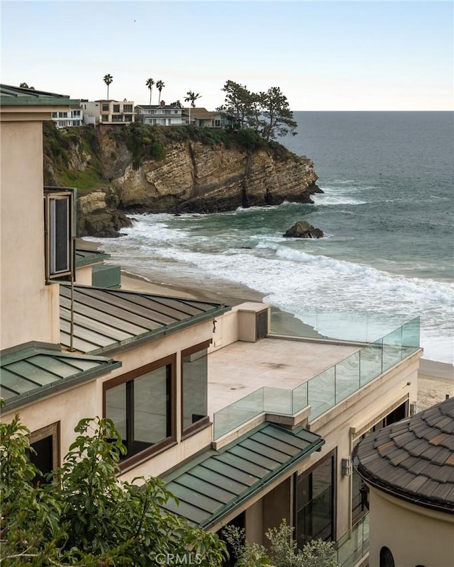 view of patio / terrace with a beach view, a balcony, and a water view