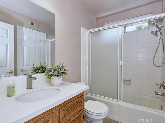 bathroom featuring visible vents, toilet, vanity, and bath / shower combo with glass door