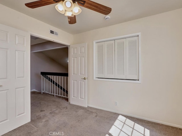 carpeted empty room featuring a ceiling fan, visible vents, and baseboards