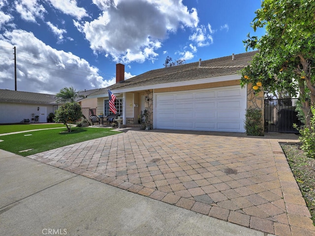 single story home featuring a front lawn, a chimney, decorative driveway, stone siding, and an attached garage