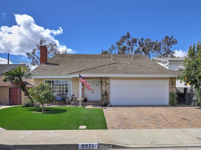 single story home featuring fence, an attached garage, a chimney, a front lawn, and decorative driveway