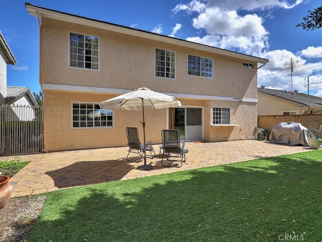 back of property with stucco siding, a patio area, a yard, and fence