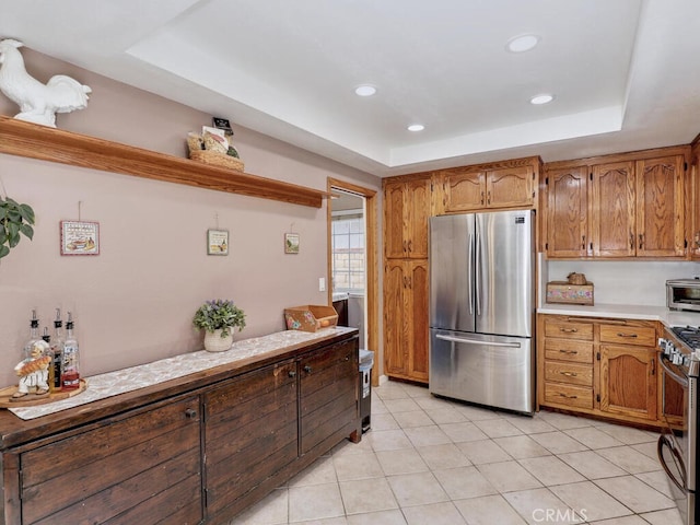 kitchen with a raised ceiling, light tile patterned floors, light countertops, and stainless steel appliances