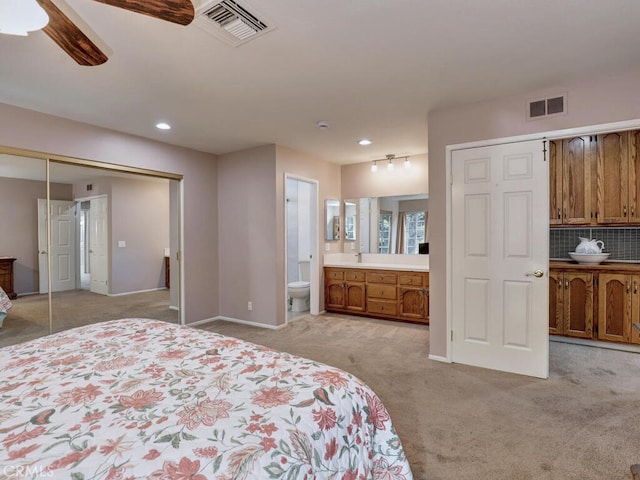 bedroom featuring light carpet, visible vents, connected bathroom, and a closet