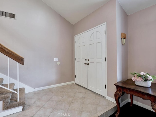 entryway with stairs, light tile patterned floors, baseboards, and visible vents