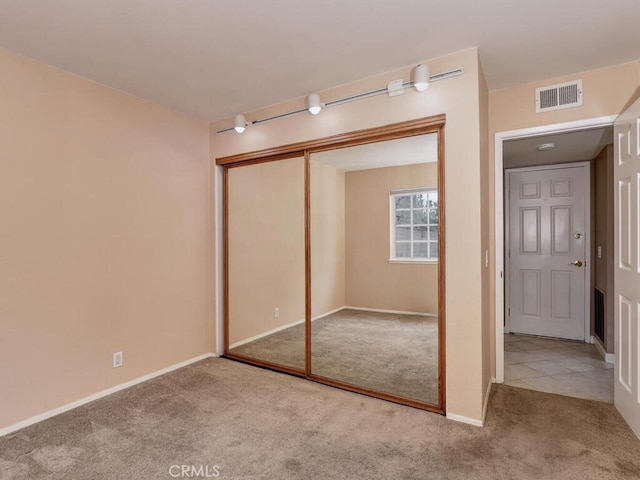 unfurnished bedroom featuring a closet, visible vents, baseboards, and carpet floors