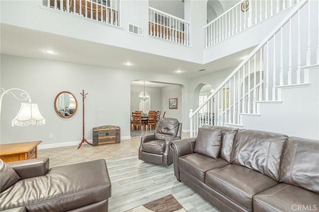 living area featuring stairway, wood finished floors, visible vents, baseboards, and arched walkways