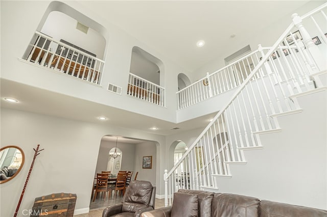 living room with visible vents, recessed lighting, stairway, arched walkways, and a towering ceiling