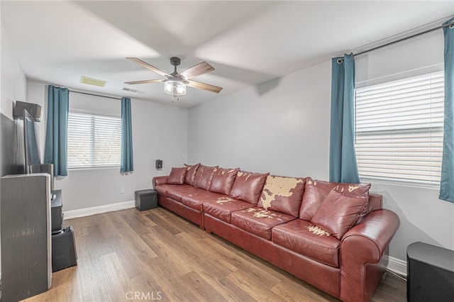 living area with visible vents, baseboards, light wood-style floors, and ceiling fan