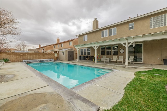 view of swimming pool featuring a fenced in pool, fence, a shed, an outdoor structure, and a patio area