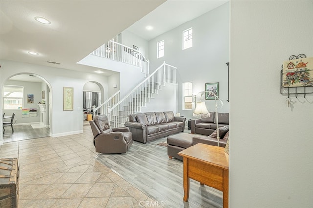 living area with arched walkways, visible vents, stairway, and a wealth of natural light