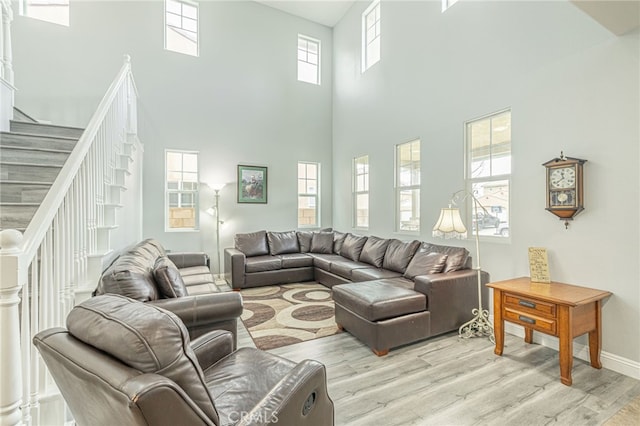 living area with stairway, baseboards, and light wood-style floors