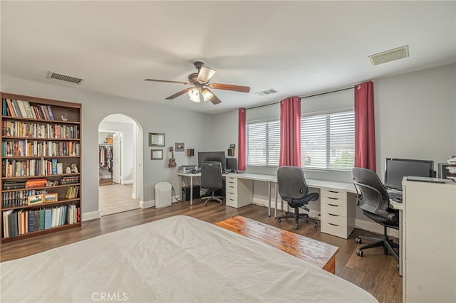 bedroom featuring visible vents, arched walkways, and wood finished floors