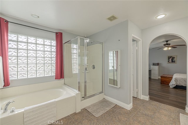 ensuite bathroom with visible vents, plenty of natural light, a garden tub, and a ceiling fan