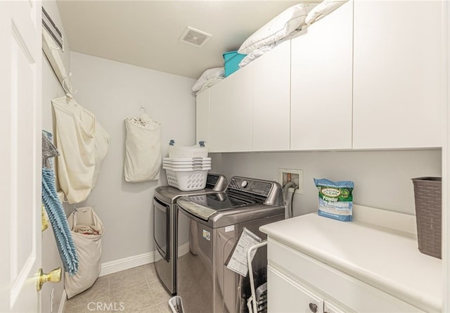 washroom with baseboards, visible vents, light tile patterned flooring, cabinet space, and washer and clothes dryer