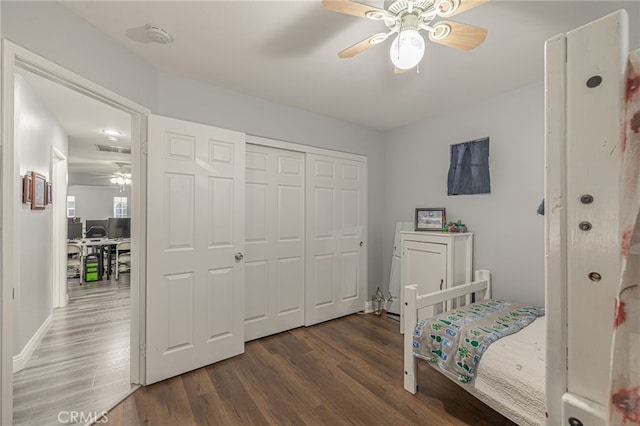 bedroom with ceiling fan, wood finished floors, a closet, and baseboards