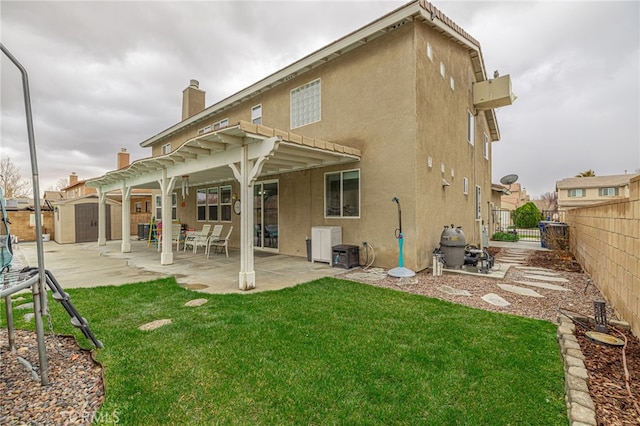 rear view of property featuring a patio area, an outbuilding, stucco siding, and a shed