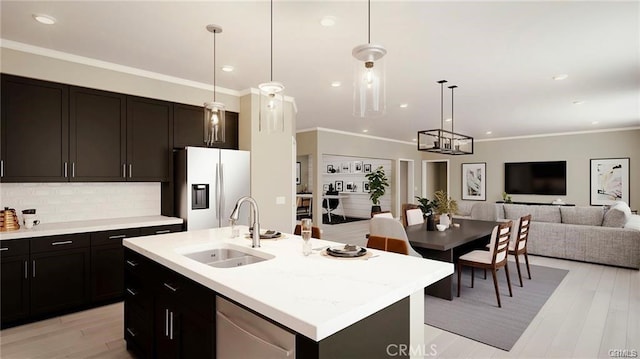 kitchen with light countertops, open floor plan, appliances with stainless steel finishes, and a sink