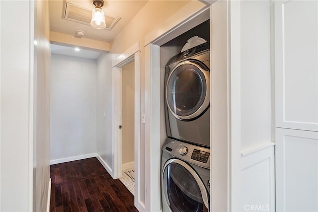 laundry room featuring stacked washer / dryer, visible vents, baseboards, laundry area, and dark wood-style flooring