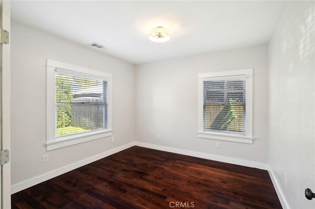 empty room featuring visible vents, baseboards, and wood finished floors