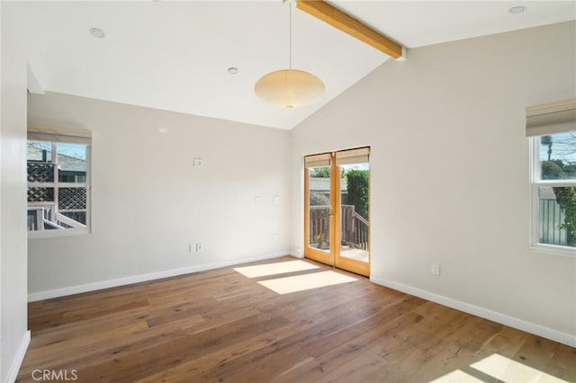 spare room with beamed ceiling, plenty of natural light, baseboards, and wood finished floors