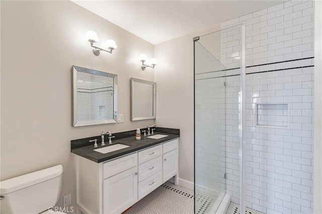 bathroom featuring double vanity, a shower stall, toilet, and a sink