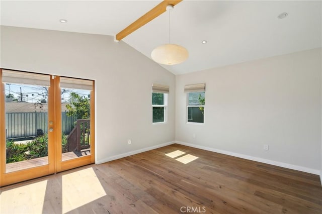 spare room featuring lofted ceiling with beams, baseboards, a healthy amount of sunlight, and wood finished floors