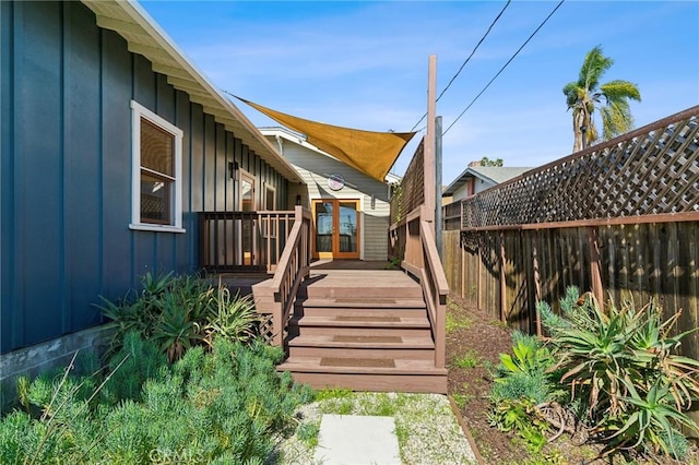 exterior space featuring a wooden deck, board and batten siding, and fence