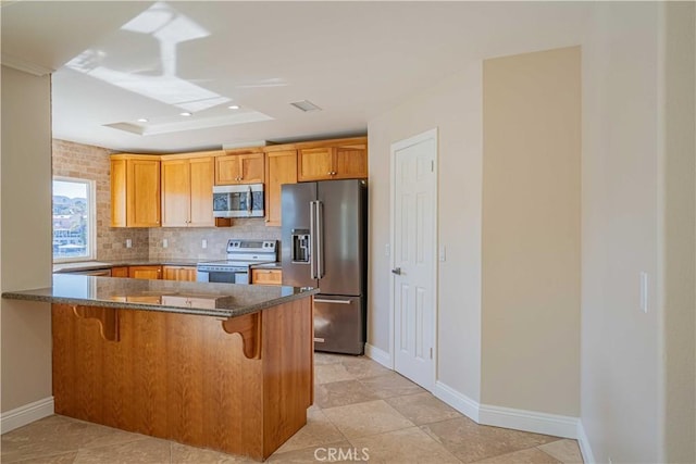 kitchen with a kitchen breakfast bar, stainless steel appliances, a peninsula, decorative backsplash, and baseboards