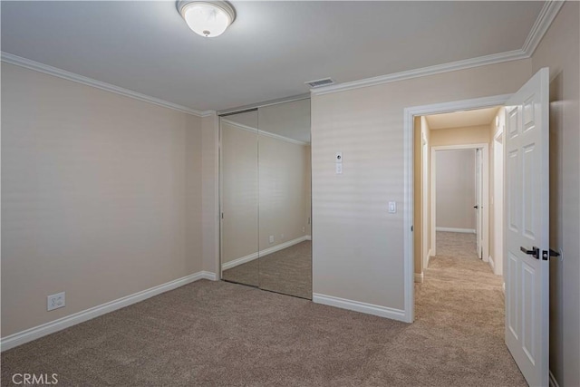 unfurnished bedroom with a closet, baseboards, crown molding, and carpet