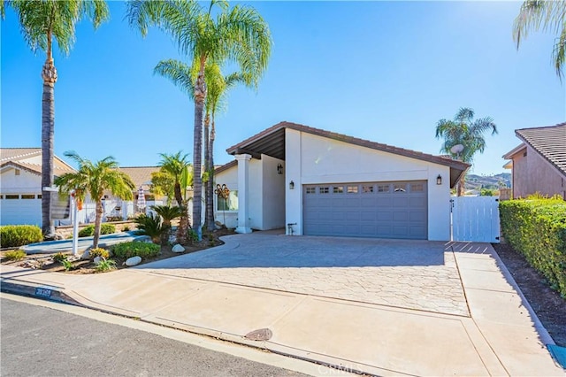 mid-century modern home with an attached garage, fence, driveway, and stucco siding