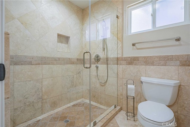 bathroom featuring toilet, tile walls, wainscoting, and a shower stall