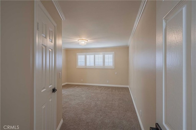 carpeted spare room featuring baseboards and crown molding