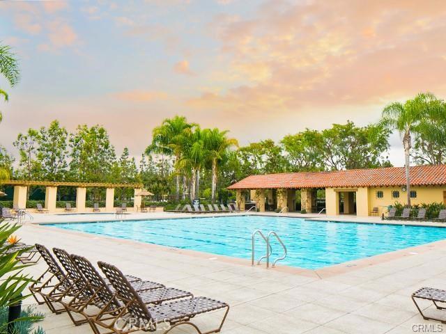 pool at dusk featuring a community pool and a patio area