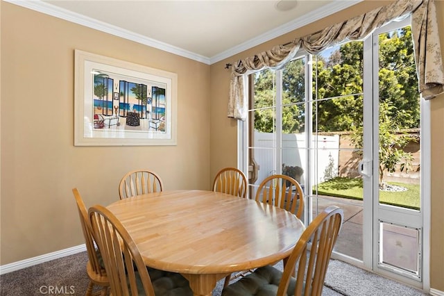 carpeted dining area with crown molding and baseboards