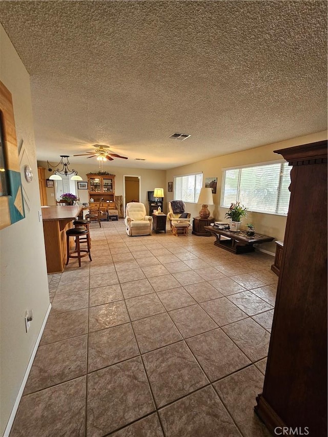 unfurnished living room featuring tile patterned flooring, baseboards, visible vents, and a textured ceiling