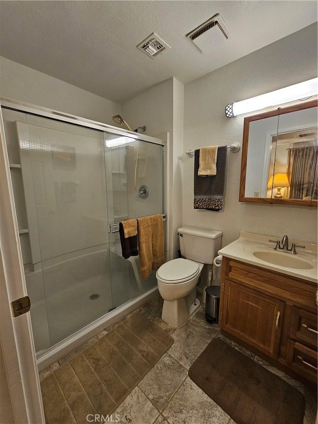 full bathroom featuring visible vents, a stall shower, toilet, and a textured ceiling