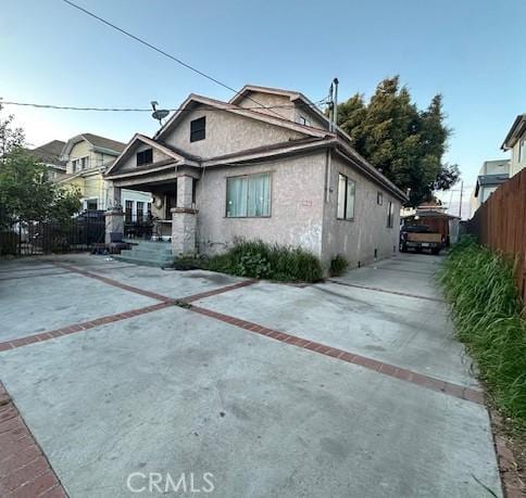 view of front of property with stucco siding, concrete driveway, and fence