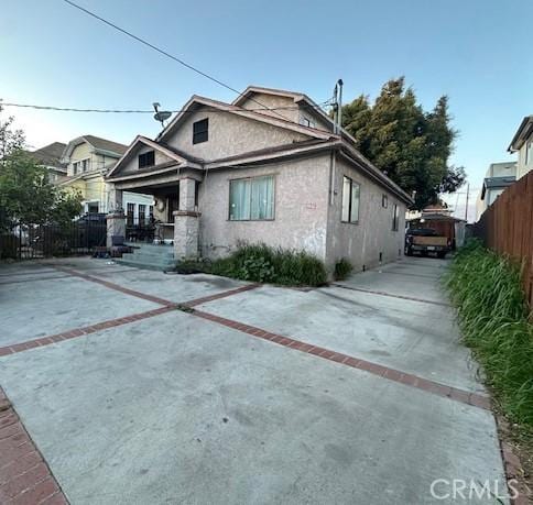 exterior space featuring stucco siding, concrete driveway, and fence