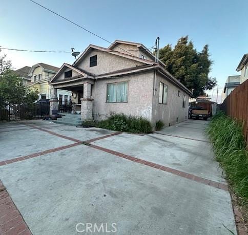 view of front of property featuring stucco siding, concrete driveway, and fence