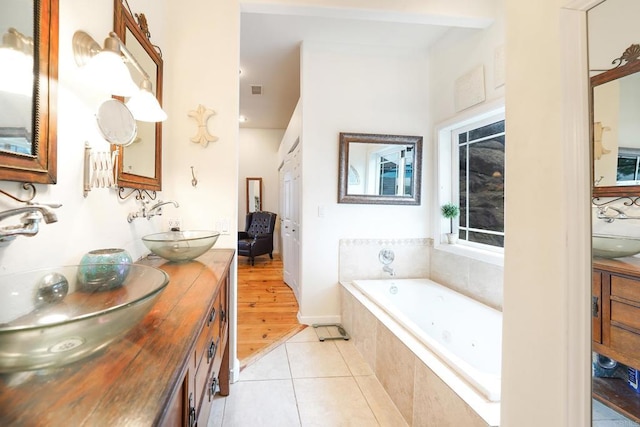 full bath featuring tile patterned floors, a garden tub, and a sink